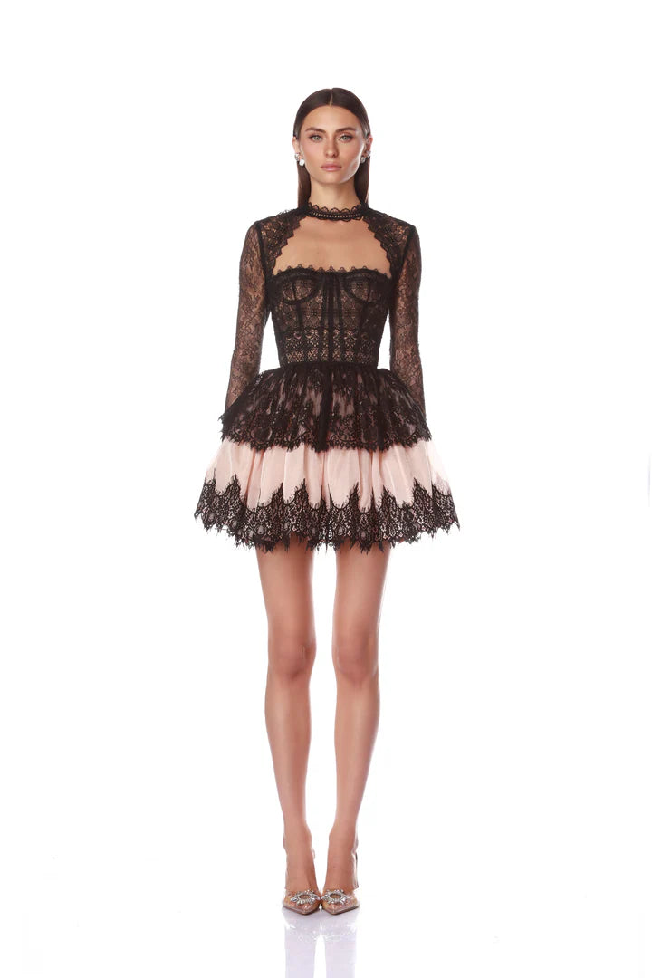 Woman wearing a black lace dress with sheer panels on a white background