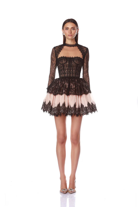 Woman wearing a black lace dress with sheer panels on a white background